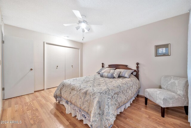 bedroom with ceiling fan, light wood-type flooring, a textured ceiling, and a closet