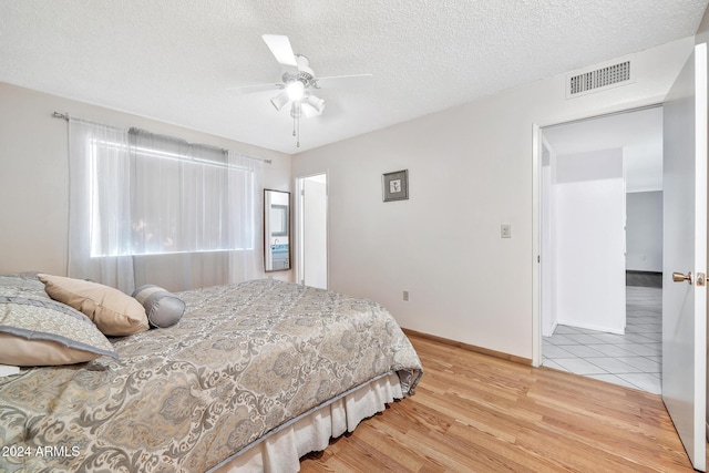 bedroom with ceiling fan, a textured ceiling, and hardwood / wood-style flooring