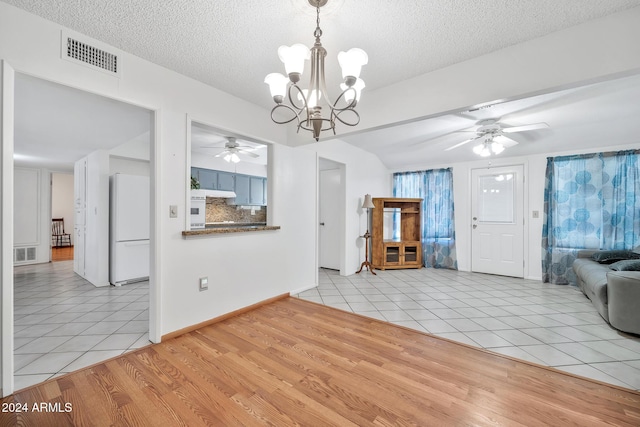 unfurnished living room with ceiling fan with notable chandelier, light hardwood / wood-style floors, and a textured ceiling