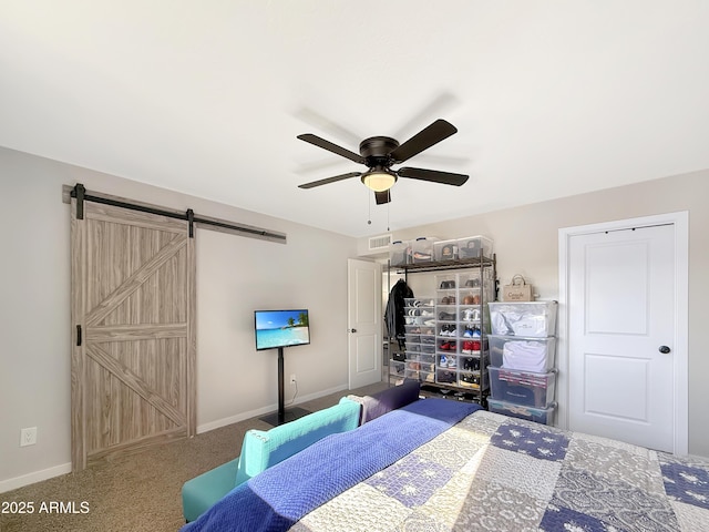 carpeted bedroom with a barn door and ceiling fan