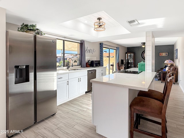 kitchen with sink, stainless steel fridge, a breakfast bar area, dishwasher, and white cabinetry