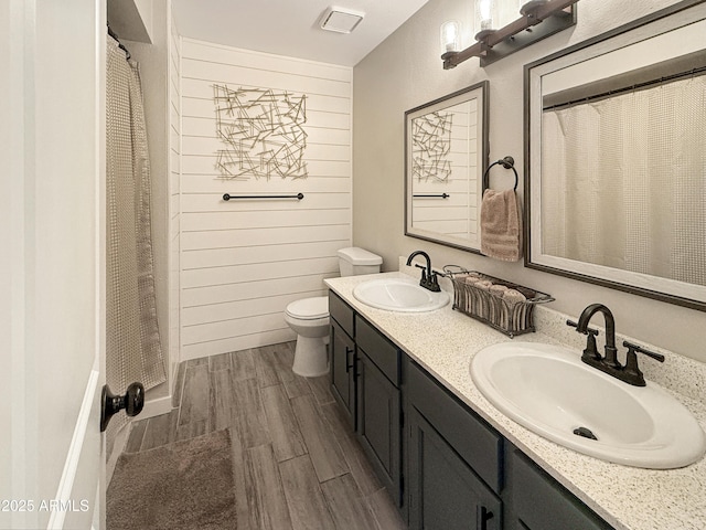 bathroom featuring toilet, vanity, and wooden walls