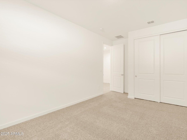 unfurnished bedroom featuring light colored carpet and a closet