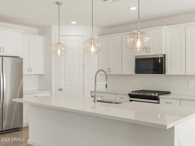 kitchen with pendant lighting, stainless steel appliances, sink, and white cabinets