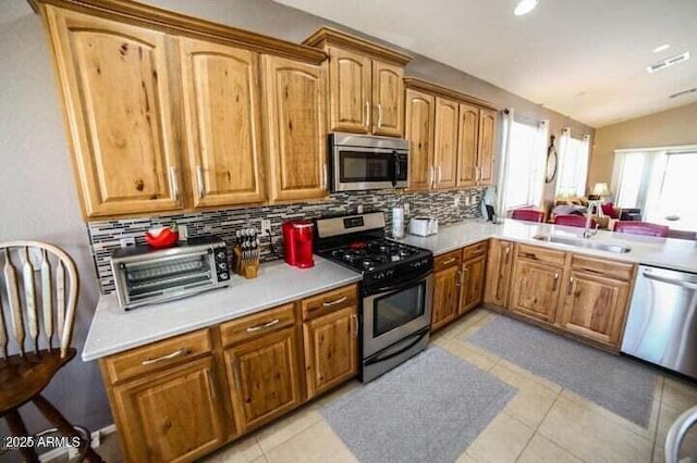 6731 S 37th Dr, Phoenix, AZ 85041 - kitchen with appliances with stainless steel finishes, decorative backsplash, light countertops, brown cabinetry, and light tile patterned flooring
