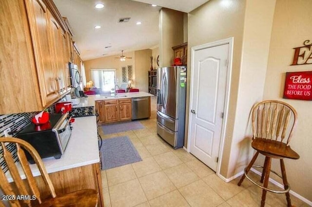 6731 S 37th Dr, Phoenix, AZ 85041 - kitchen featuring appliances with stainless steel finishes, a peninsula, lofted ceiling, light countertops, and brown cabinets