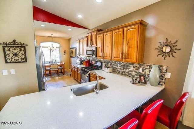 6731 S 37th Dr, Phoenix, AZ 85041 - kitchen with stainless steel appliances, brown cabinets, lofted ceiling, a chandelier, and backsplash