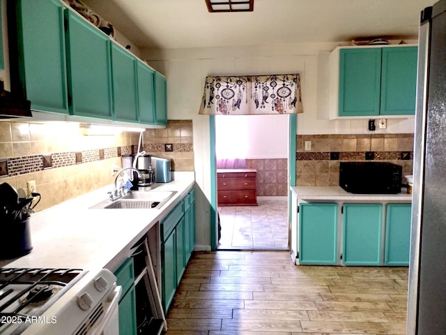 111 W 9th St, Ajo, AZ 85321 - kitchen with a sink, light wood-style floors, light countertops, decorative backsplash, and black microwave