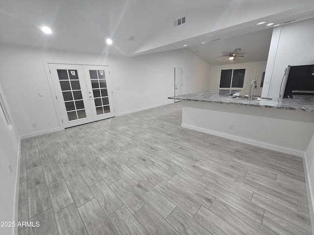 unfurnished living room featuring ceiling fan, sink, lofted ceiling, and french doors