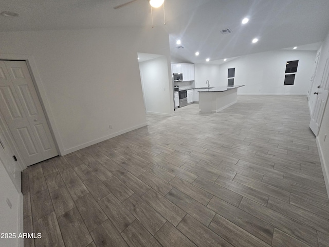 unfurnished living room featuring ceiling fan and vaulted ceiling