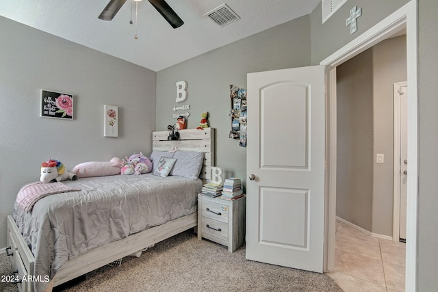 bedroom featuring light tile patterned floors, visible vents, lofted ceiling, and a ceiling fan