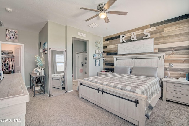 bedroom featuring ceiling fan, visible vents, light colored carpet, and wood walls