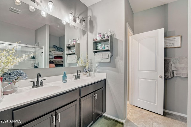 bathroom featuring double vanity, a stall shower, tile patterned floors, and a sink