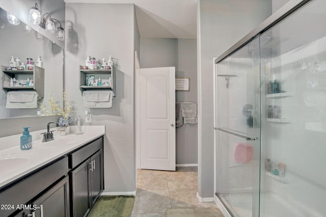 full bath featuring double vanity, a stall shower, baseboards, and a sink