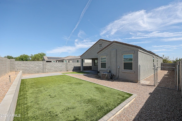 back of house with cooling unit, a yard, a fenced backyard, and a gate