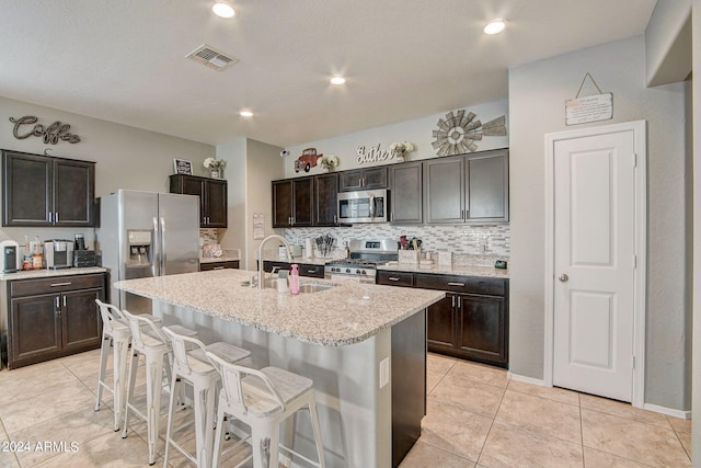 kitchen with a breakfast bar area, visible vents, a sink, decorative backsplash, and stainless steel appliances