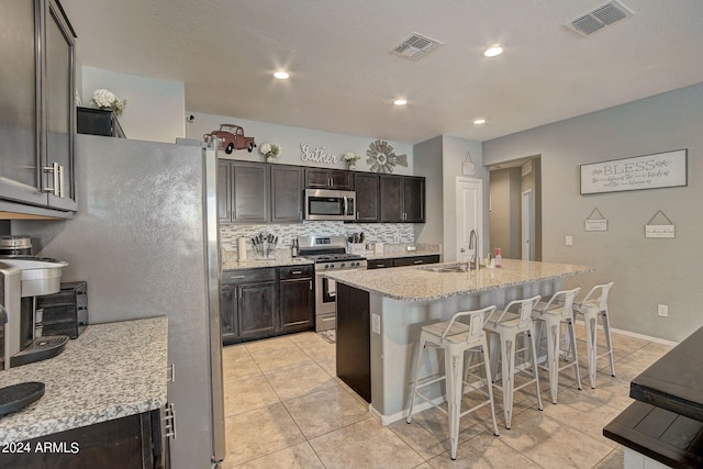 kitchen with a sink, visible vents, a kitchen bar, and stainless steel appliances