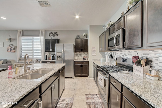 kitchen with light tile patterned floors, light stone countertops, visible vents, a sink, and appliances with stainless steel finishes