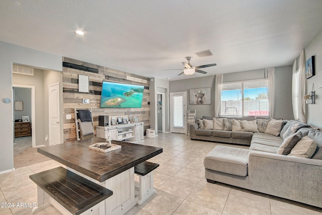 living area featuring an accent wall, wooden walls, light tile patterned flooring, and visible vents