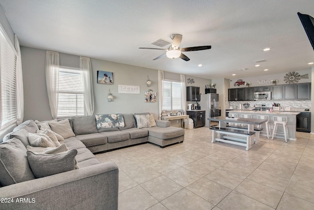 living room featuring plenty of natural light, a ceiling fan, visible vents, and light tile patterned floors