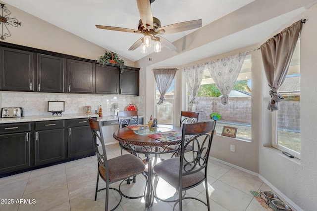 tiled dining space with ceiling fan and vaulted ceiling