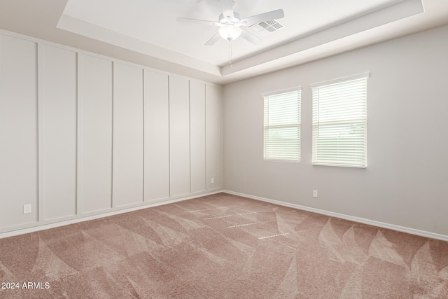 unfurnished room featuring a tray ceiling, ceiling fan, and light carpet