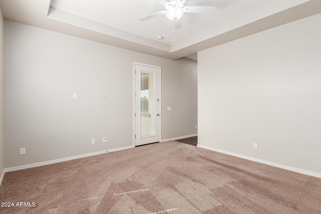 carpeted empty room featuring ceiling fan and a tray ceiling