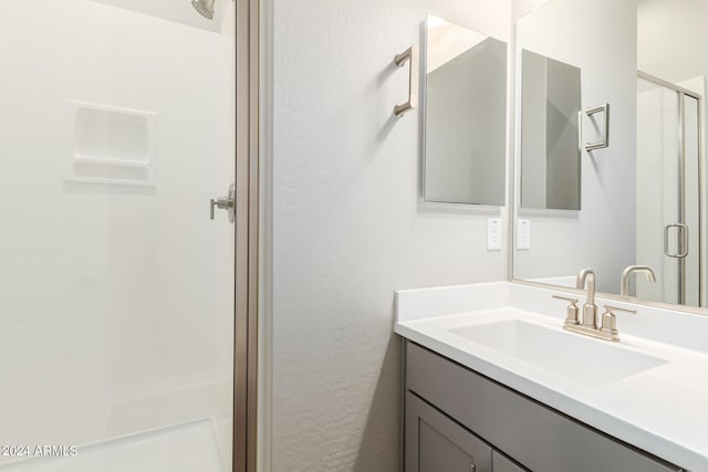 bathroom featuring a shower with door and vanity