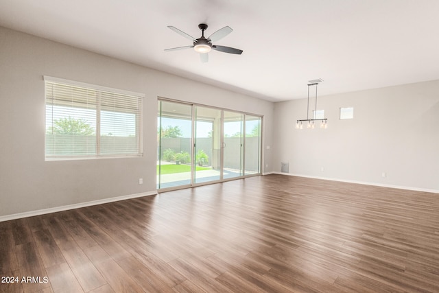 empty room with dark hardwood / wood-style flooring, ceiling fan, and plenty of natural light