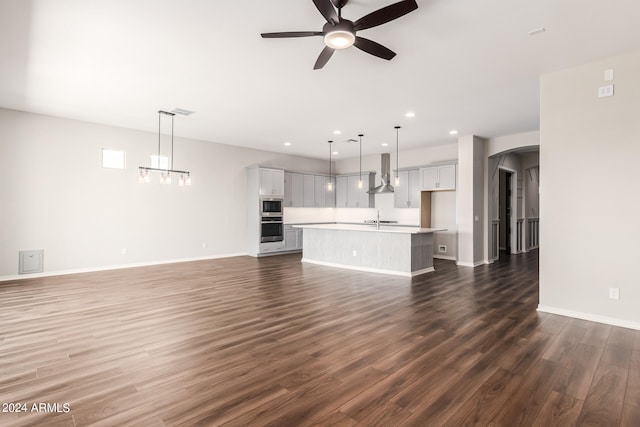 unfurnished living room featuring ceiling fan and dark wood-type flooring