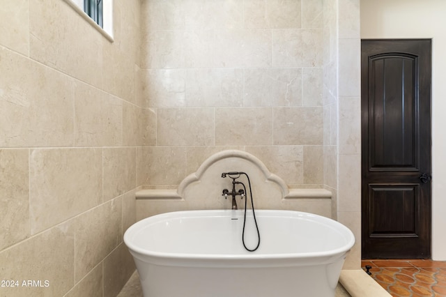 bathroom with tile walls, a bathing tub, and tile patterned flooring