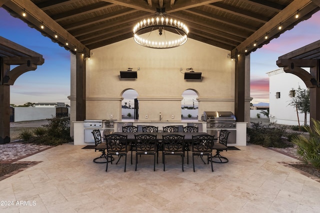 patio terrace at dusk with a grill, a bar, and area for grilling