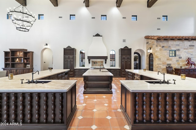 kitchen featuring a high ceiling, sink, a large island with sink, and beam ceiling