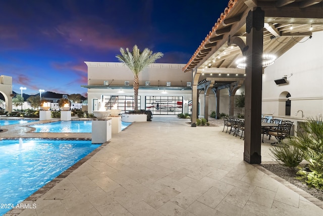 pool at dusk featuring a patio