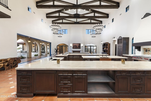 kitchen featuring high vaulted ceiling, sink, dark brown cabinetry, and beamed ceiling