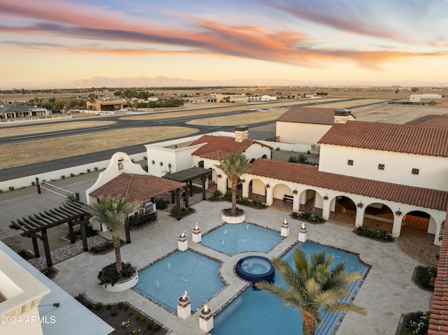 pool at dusk featuring a patio area, a community hot tub, and a pergola