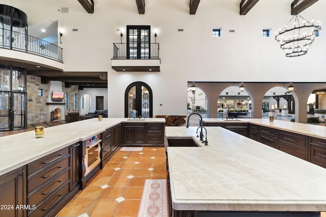 kitchen with sink, beam ceiling, and a kitchen island with sink