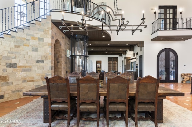 tiled dining space featuring a chandelier, french doors, and a towering ceiling