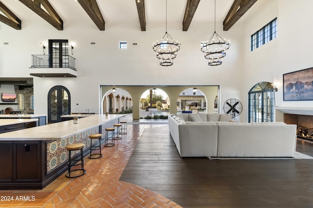 living room featuring french doors, a towering ceiling, and beamed ceiling