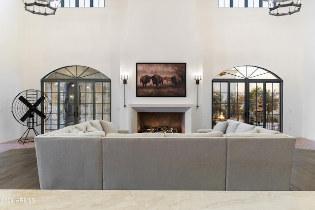 living room featuring hardwood / wood-style floors, a towering ceiling, and french doors