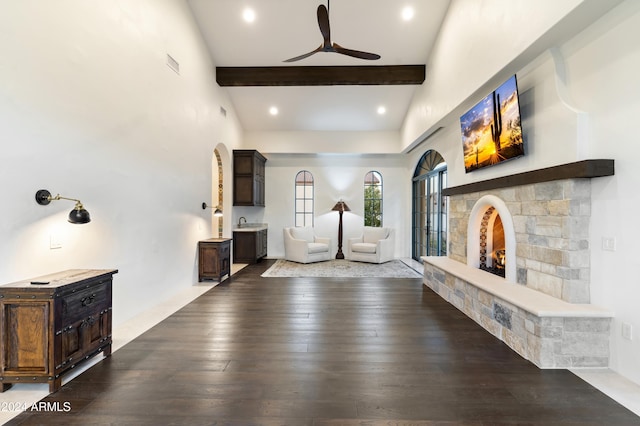 interior space with ceiling fan, a towering ceiling, hardwood / wood-style flooring, and beamed ceiling