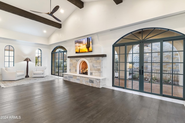 unfurnished living room featuring a stone fireplace, ceiling fan, wood-type flooring, high vaulted ceiling, and beam ceiling