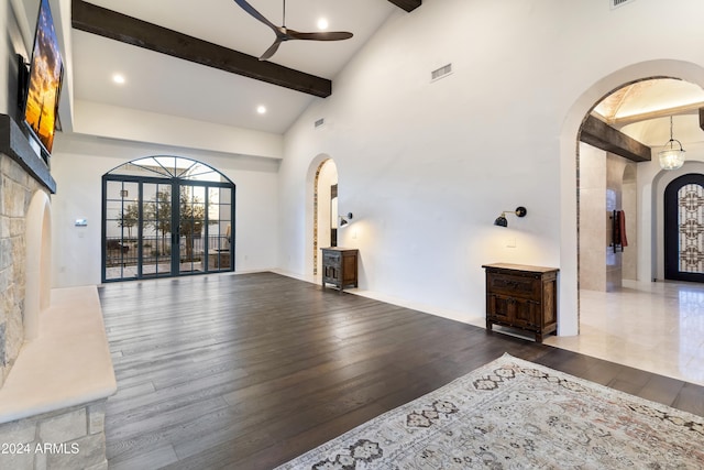 interior space featuring ceiling fan, french doors, a towering ceiling, and dark wood-type flooring