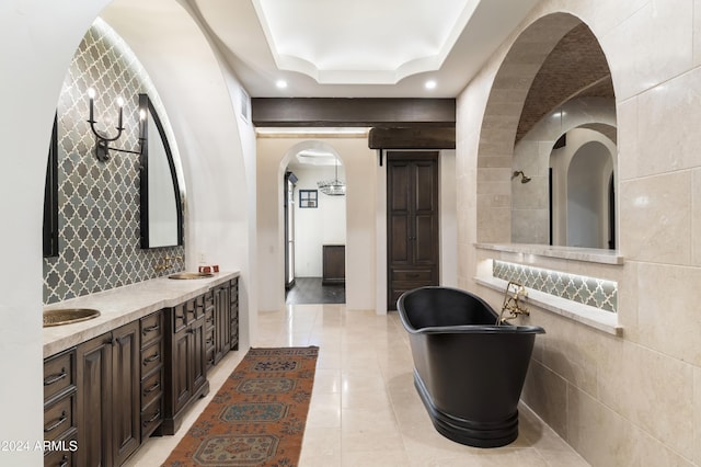 interior space featuring tile walls, a bathtub, a raised ceiling, and vanity