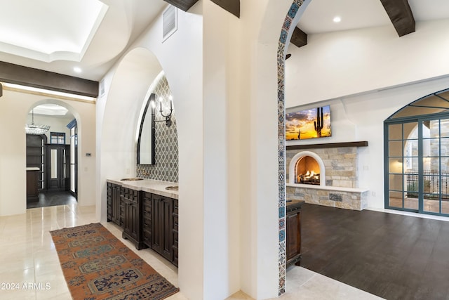 bar with a fireplace, tasteful backsplash, sink, light tile patterned flooring, and dark brown cabinets