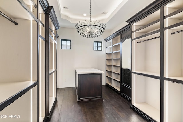 spacious closet featuring dark wood-type flooring and an inviting chandelier