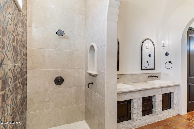 bathroom with a tile shower and vanity