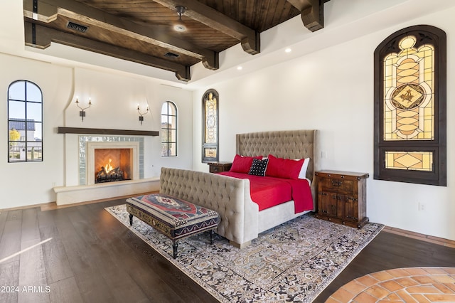 bedroom featuring beam ceiling, a high end fireplace, wood-type flooring, and wood ceiling