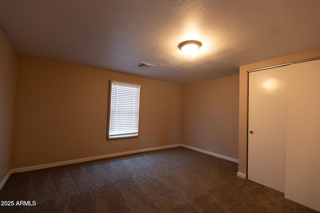 349 E Central Ave, Coolidge, AZ 85128 - unfurnished bedroom with a closet, a textured ceiling, visible vents, baseboards, and dark colored carpet