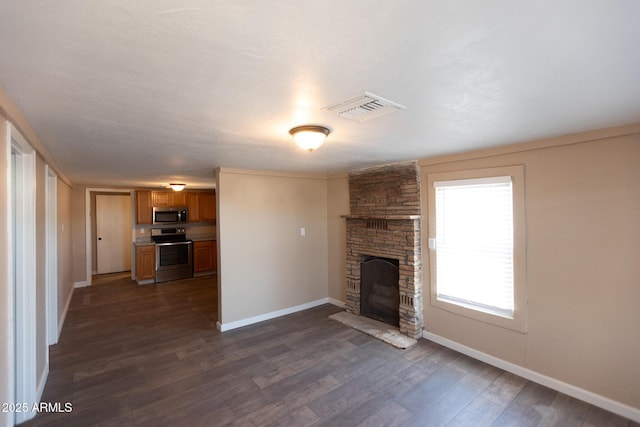 349 E Central Ave, Coolidge, AZ 85128 - unfurnished living room featuring baseboards, a stone fireplace, visible vents, and dark wood-style flooring